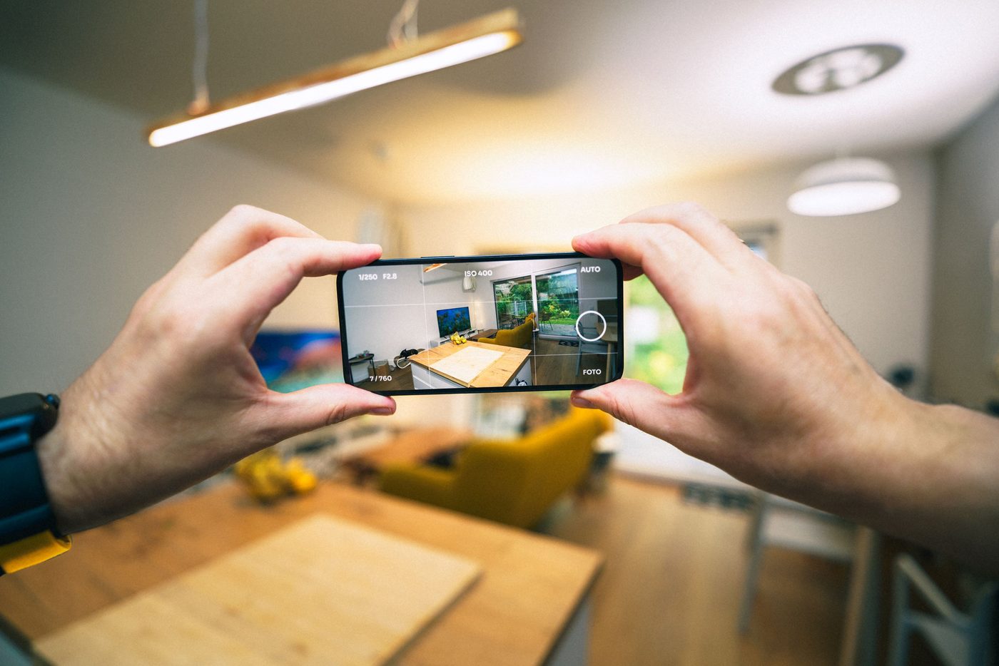 Hands using a smartphone to document a furnished room